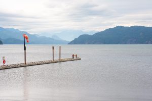 Couple and dog standing on edge of pier at Harrison Hot Springs shorefront